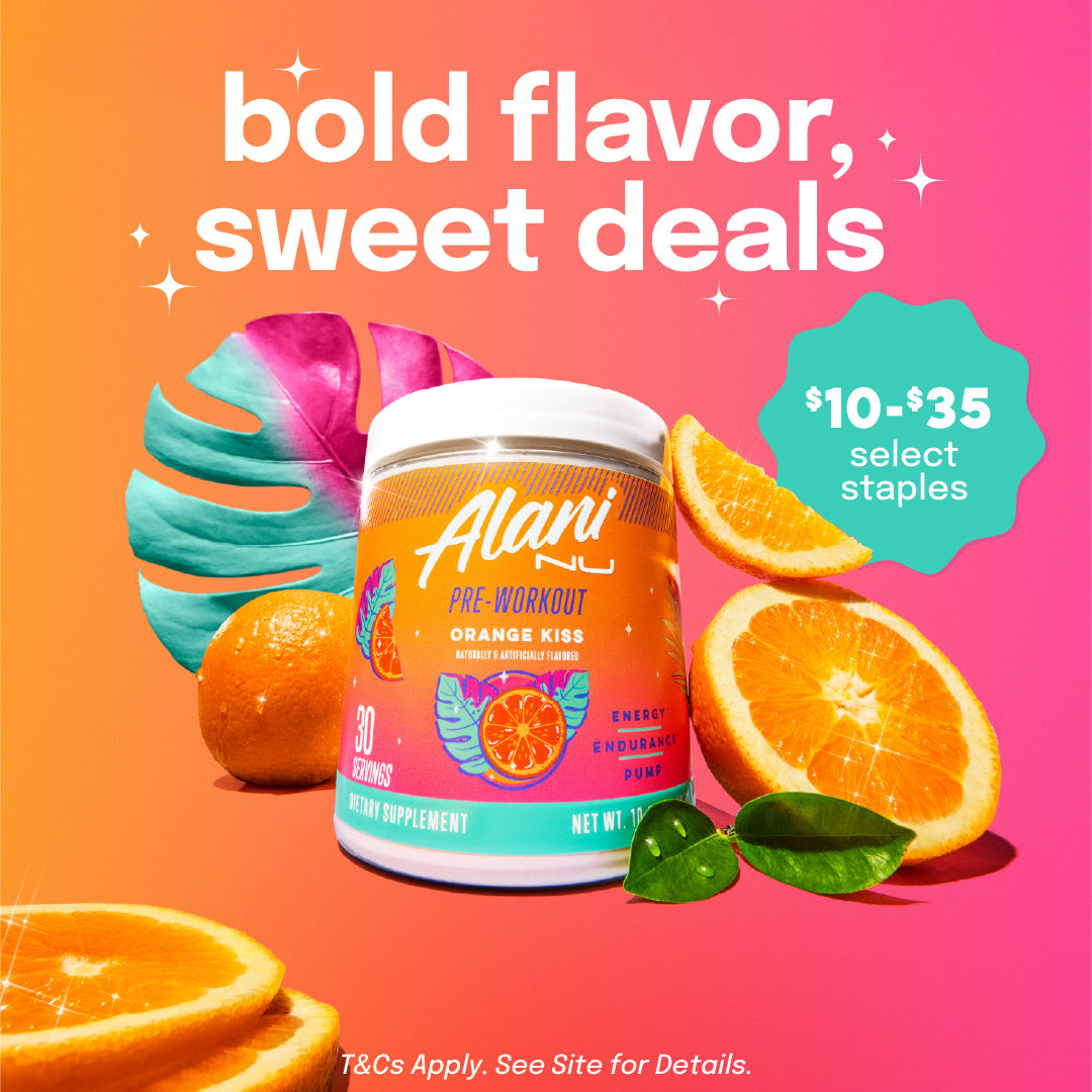 A tub of Orange Kiss Alani Nu Pre-Workout surrounded by orange slices and a palm leaf.