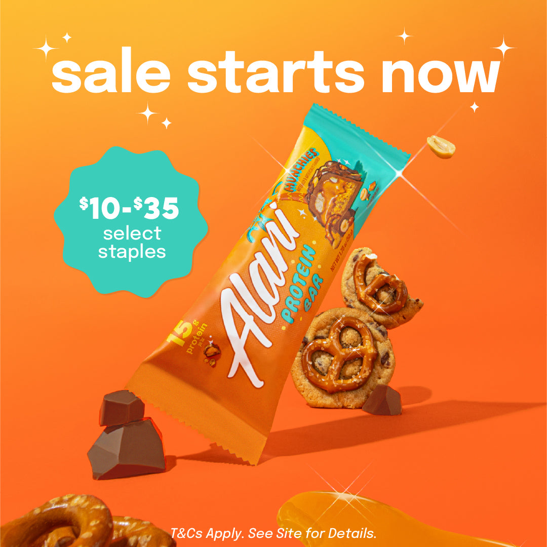 A Munchies Alani Nu Protein Bar surrounded by chunks of chocolate, pretzels, and cookies.