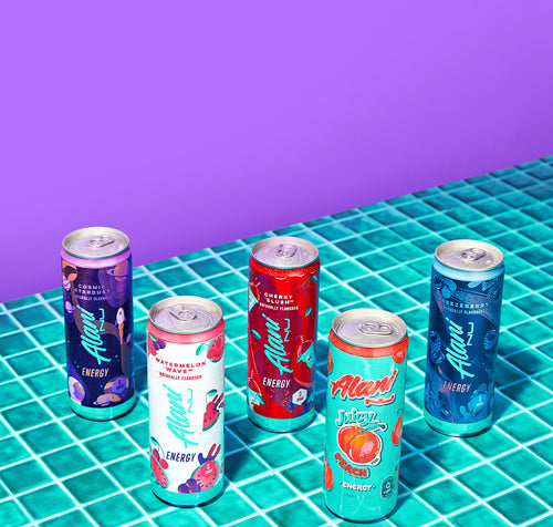 Five chilled Alani Nu Energy Drink cans resting on a teal tiled countertop.