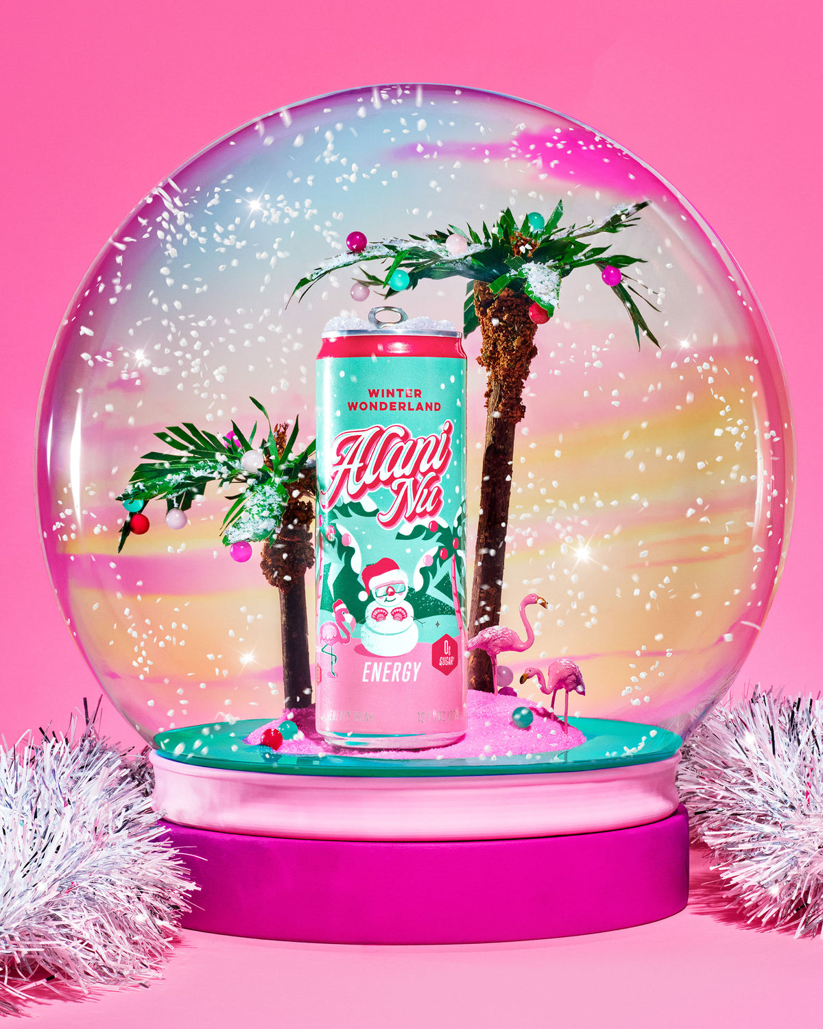 Alani Nu's limited-edition Winter Wonderland Energy inside a tropical snow globe. Faux flurries fall on paper palm trees and flamingo figurines.