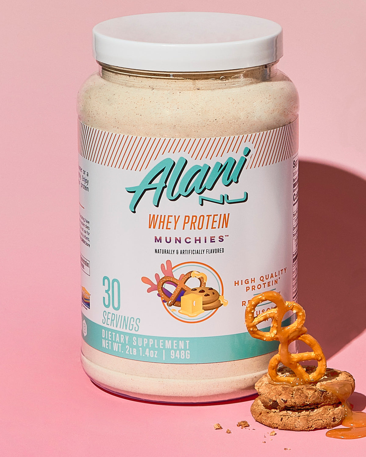 Whey Protein in Munchies flavor container sitting next to a cookie &amp; pretzels.