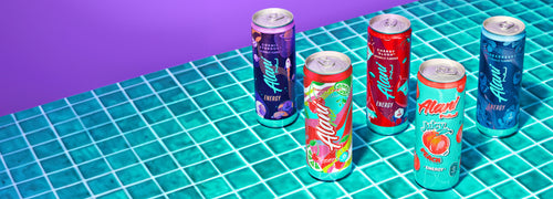 Alani Nu's Cosmic Stardust, Cherry Twist, Cherry Slush, Juicy Peach, and Breezeberry Energy Drinks on a tiled countertop. 