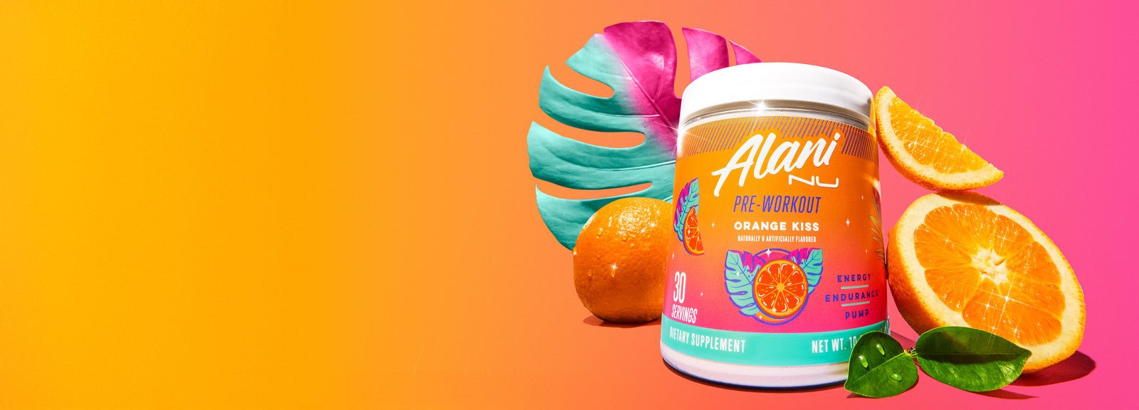 A tub of Orange Kiss Alani Nu Pre-Workout surrounded by orange slices and a palm leaf.