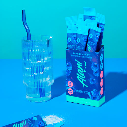 Alani energy stick packaging with a glass and straw on a blue background