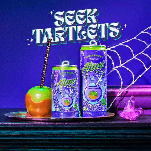 A caramel apple and both sizes of Alani Nu's seasonal Witch's Brew Energy (12oz and 8.4oz) on a silver platter. Text reads, "Seek Tartlets."
