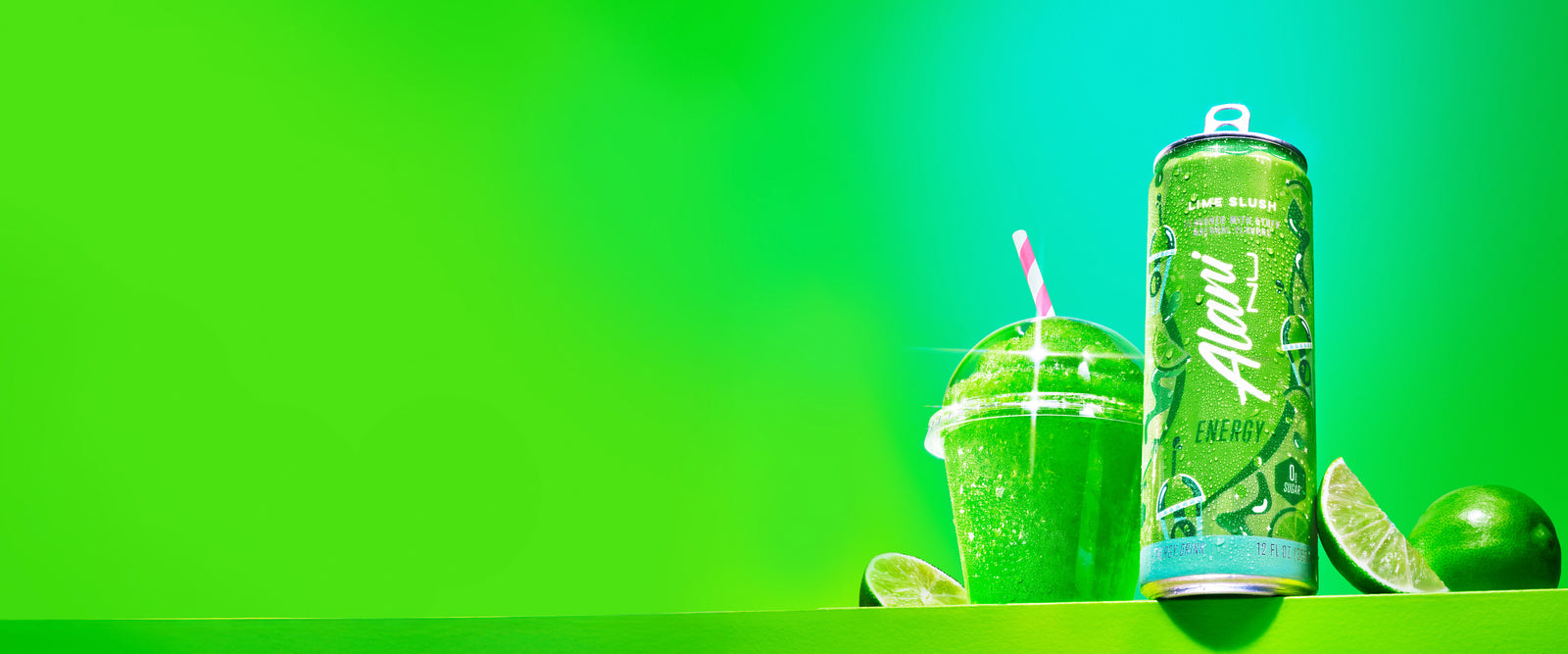 A can of Alani Energy's new spring flavor, Lime Slush, on a bright green shelf next a straw-topped, citrus-flavored slushie and limes. 
