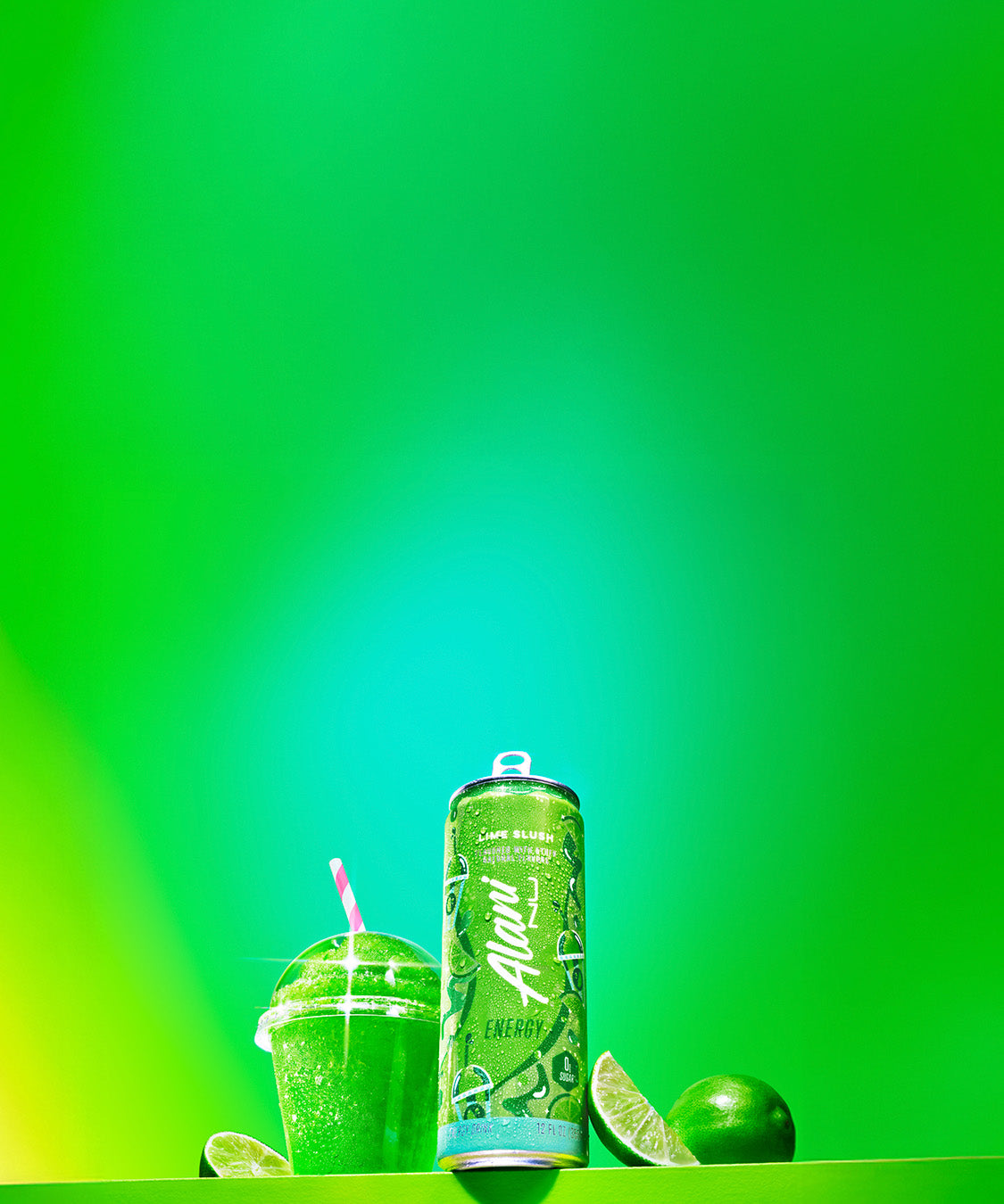 A can of Alani Energy's new spring flavor, Lime Slush, on a bright green shelf next a straw-topped, citrus-flavored slushie and limes. 
