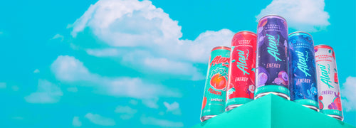 Five sugar-free Alani Energy Drink cans on a seafoam shelf in front of a blue sky.