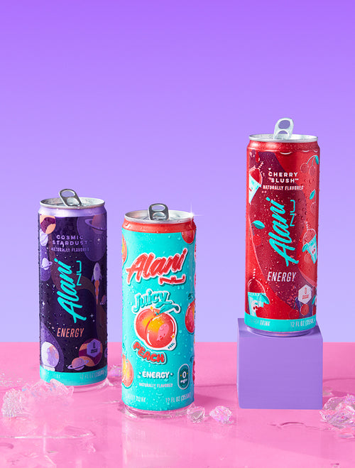 Three cans of Alani Energy drinks in different flavors, Cosmic Stardust, Juicy Peach, and Cherry Slush, are displayed against each other.
