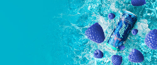 A sugar-free Breezeberry Alani Nu Energy Drink and juicy blue raspberries splashing into crisp, refreshing water.

