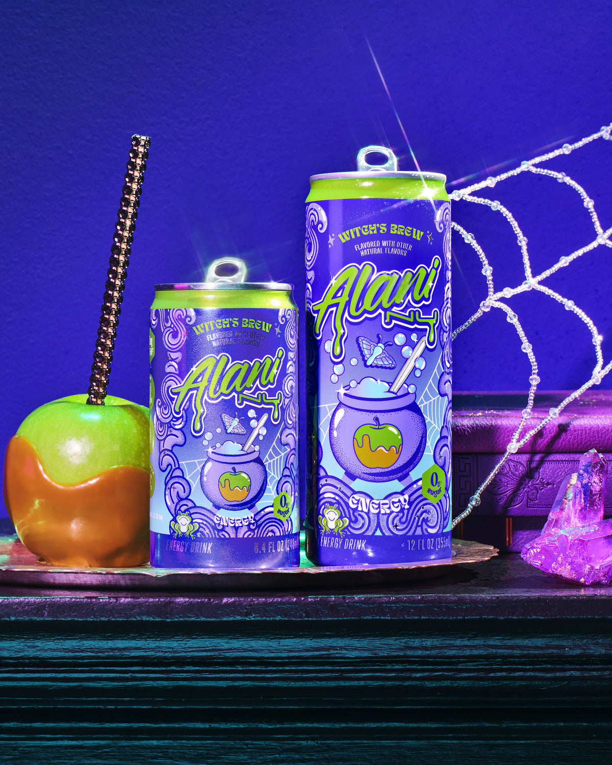 A glamorous witch lifting a half-caff Mini Witch&#39;s Brew Alani Energy from a silver platter, a full-sized Witch&#39;s Brew served alongside it.
