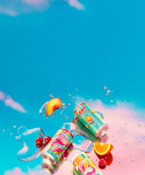 8.4oz Juicy Peach, Cherry Twist, and Sherbet Swirl Mini Energy cans resting on a mirrored surface alongside puddles of Alani Energy and fresh fruit.

