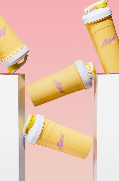A yellow shaker with Alani Nu text in front of the merchandise product. 