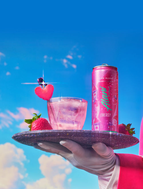 A gloved server presenting a bejeweled tray of Pink Slush Energy in a can and a glass garnished with fresh strawberries. 