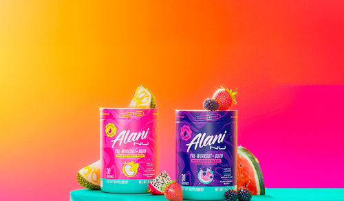 Alani Nu's thermogenic Pre-Workout+ Burn in Dragon Fruit Rush flavor and Melonberry Blast flavor shown on a pedestal with tropical fruits.
