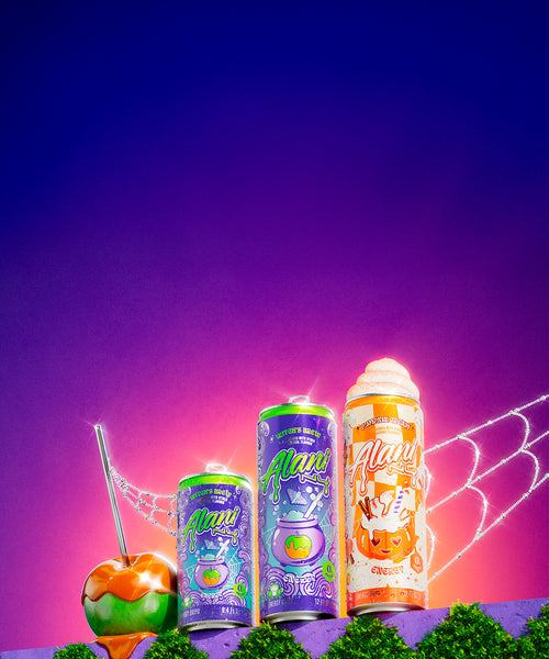 A caramel apple with Alani Nu’s 3 limited-edition fall Energy Drinks—Mini Witch’s Brew, Witch’s Brew, and new Pumpkin Cream—on a garden ledge.
