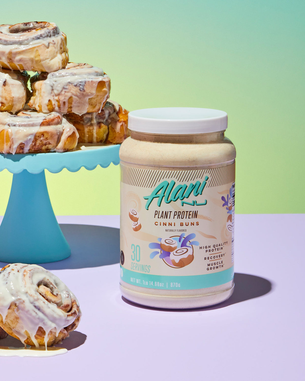 A cake plater of cinnamon rolls next to Plant Protein in Cinni Buns flavor container.