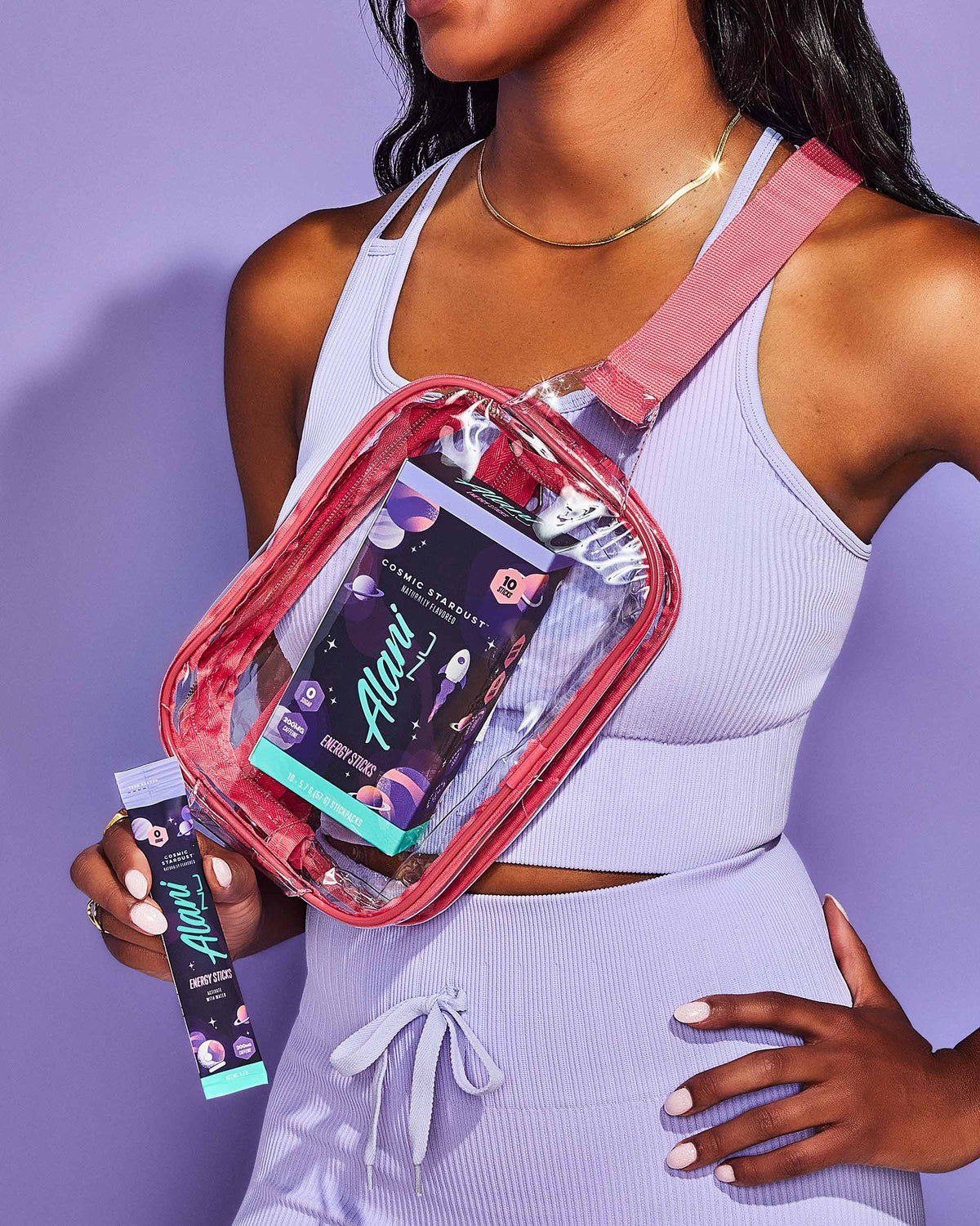 a woman in a purple top holding a clear bag of Alani Nu Energy Sticks - Cosmic Stardust.