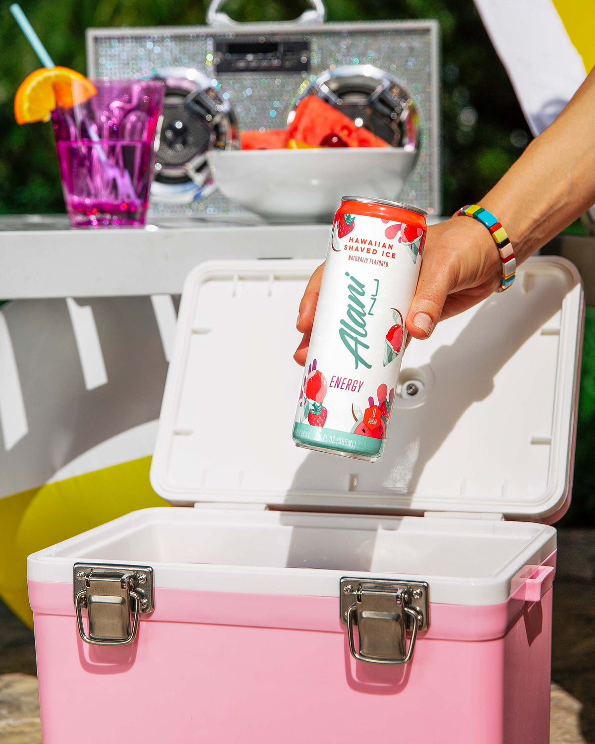 a person holding a can of Energy Drink - Hawaiian Shaved Ice by Alani Nu in a cooler.