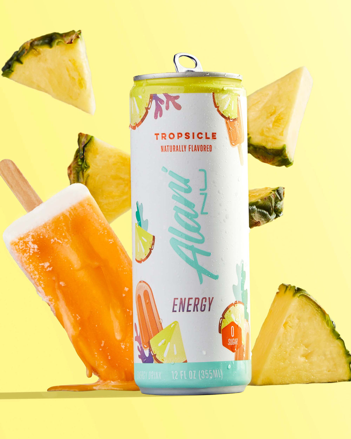 A 12 fl oz energy drink in Tropsicle flavor next to a popsicle and pineapples.
